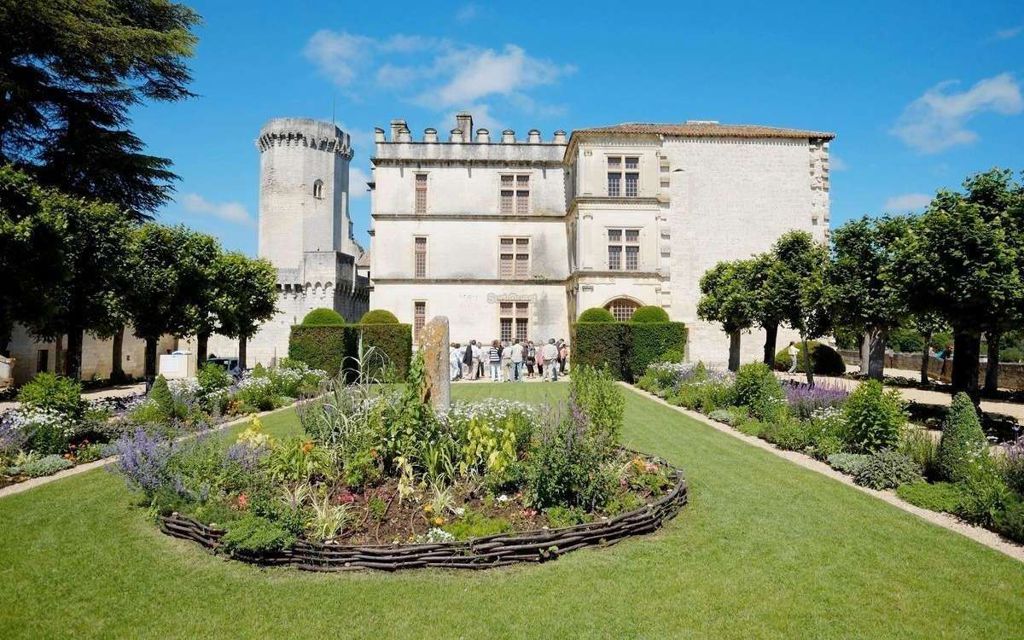 vue du château de Bourdeilles avec le jardin au premier plan. Une tour hexagonale à gauche, une partie du château à créneaux et la partie droite plus moderne
