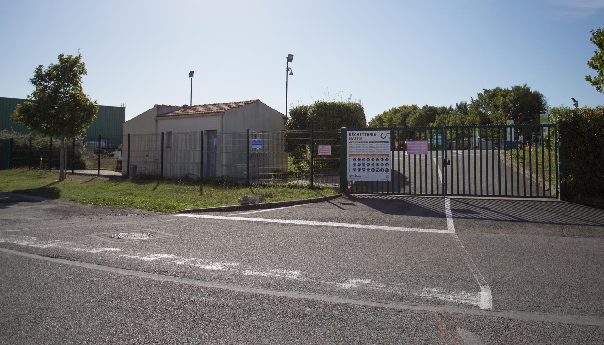 - vue de l'entrée de la déchèterie de Matha, grand portail à barreaux verts